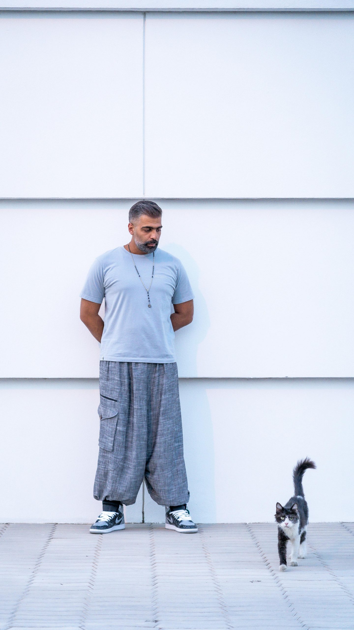 Man Standing and Looking at a Cat